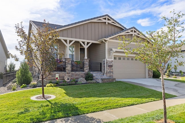 craftsman-style home with concrete driveway, an attached garage, board and batten siding, a front yard, and stone siding