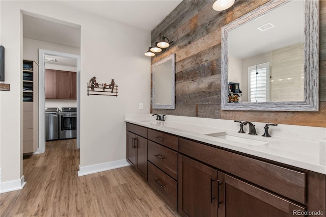 bathroom with double vanity, wood finished floors, washer and clothes dryer, and a sink