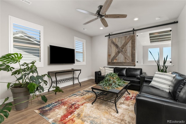 living area featuring a wealth of natural light, a ceiling fan, baseboards, and wood finished floors