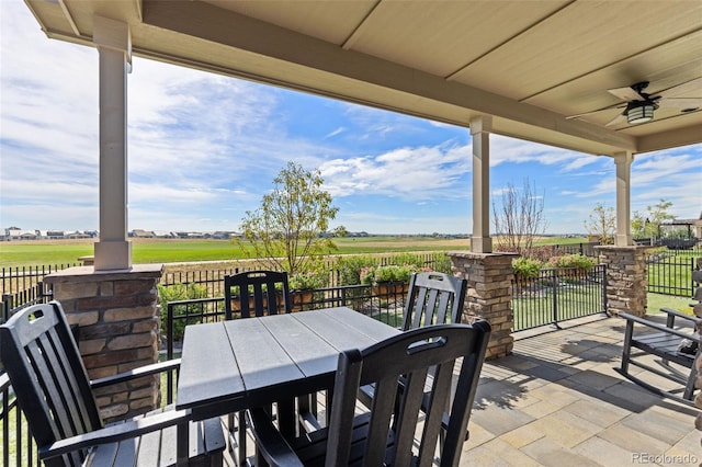 view of patio featuring a ceiling fan, outdoor dining space, and a rural view