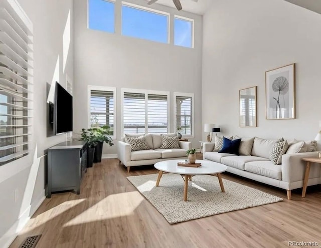 living area featuring a ceiling fan, baseboards, visible vents, and light wood finished floors