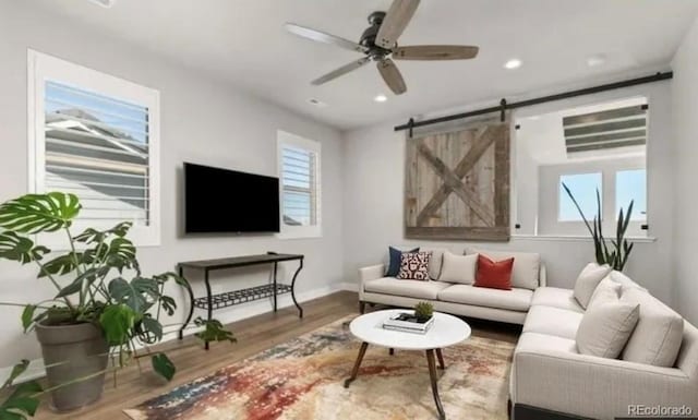 living area featuring recessed lighting, a barn door, a ceiling fan, wood finished floors, and baseboards