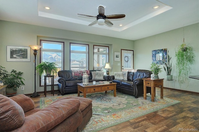 living room featuring a tray ceiling, ceiling fan, and dark wood-type flooring