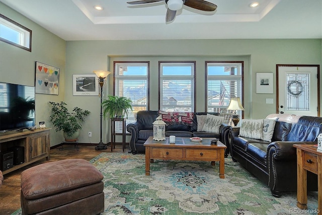 living room featuring ceiling fan and a raised ceiling