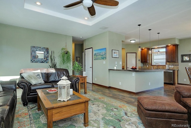 living room with dark hardwood / wood-style flooring, a raised ceiling, ceiling fan, and sink