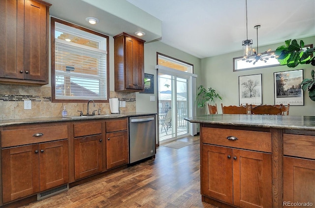 kitchen featuring dishwasher, sink, dark hardwood / wood-style flooring, a chandelier, and decorative backsplash