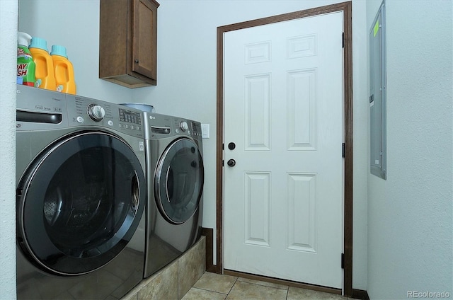 clothes washing area with washer and clothes dryer, light tile patterned floors, and cabinets