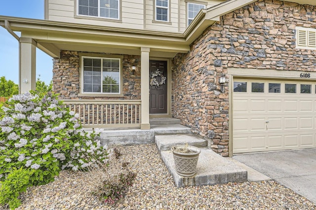 6108 S Harvest Ct, Aurora, CO 80016 - view of exterior entry with stone siding, covered porch, and driveway