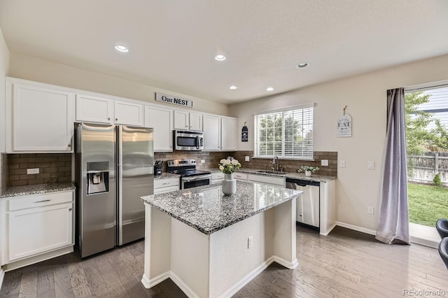 6108 S Harvest Ct, Aurora, CO 80016 - kitchen with stainless steel appliances, white cabinetry, backsplash, wood finished floors, and recessed lighting
