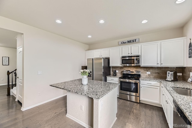 6108 S Harvest Ct, Aurora, CO 80016 - kitchen featuring stainless steel appliances, a sink, wood finished floors, light stone countertops, and white cabinetry