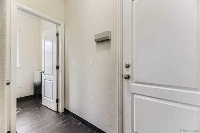 6108 S Harvest Ct, Aurora, CO 80016 - hall with dark marble finish floors, a textured wall, and baseboards