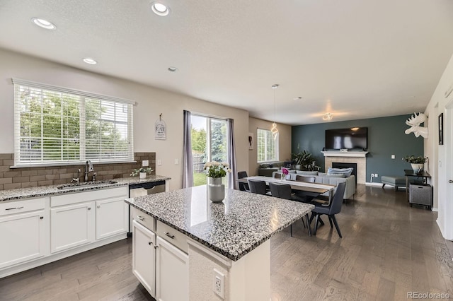 6108 S Harvest Ct, Aurora, CO 80016 - kitchen with dark wood-style flooring, open floor plan, backsplash, white cabinetry, and light stone counters