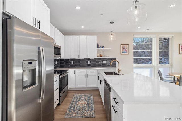 kitchen with decorative light fixtures, tasteful backsplash, white cabinetry, sink, and stainless steel appliances