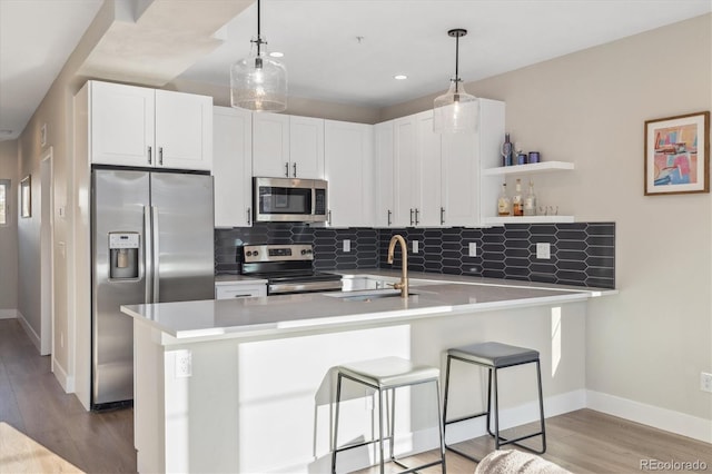 kitchen with pendant lighting, white cabinetry, kitchen peninsula, and appliances with stainless steel finishes