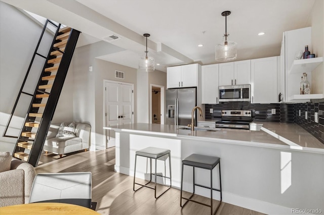 kitchen with sink, appliances with stainless steel finishes, white cabinets, decorative light fixtures, and kitchen peninsula