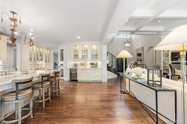 kitchen featuring dark wood-type flooring, wine cooler, beamed ceiling, arched walkways, and a sink