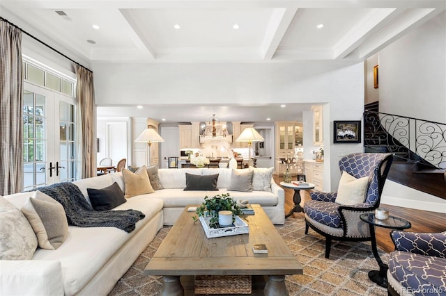 living room with stairs, beam ceiling, coffered ceiling, and a chandelier