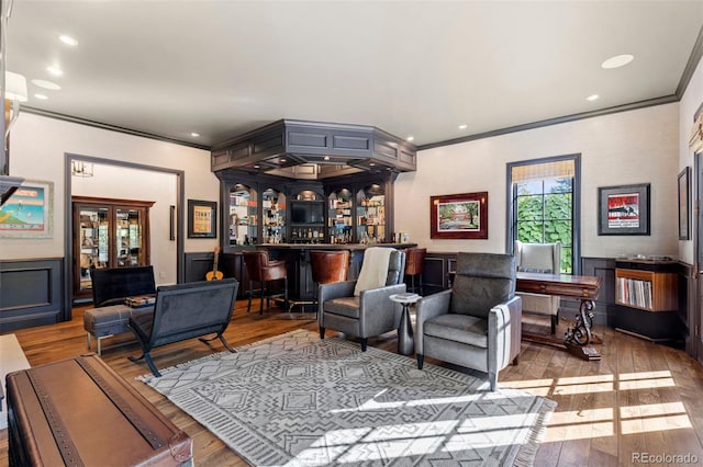 living area with a bar, hardwood / wood-style flooring, recessed lighting, and ornamental molding