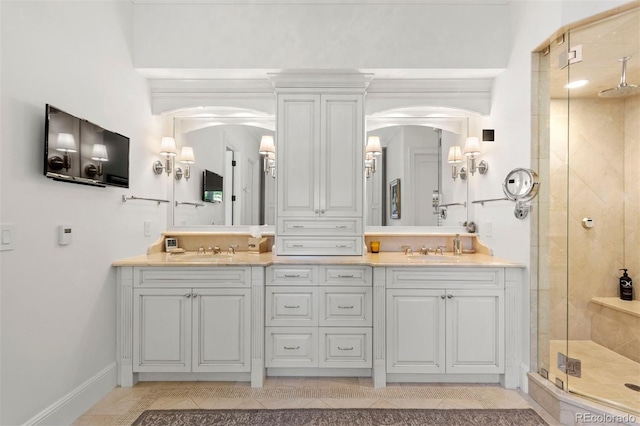 bathroom with double vanity, a shower stall, and a sink