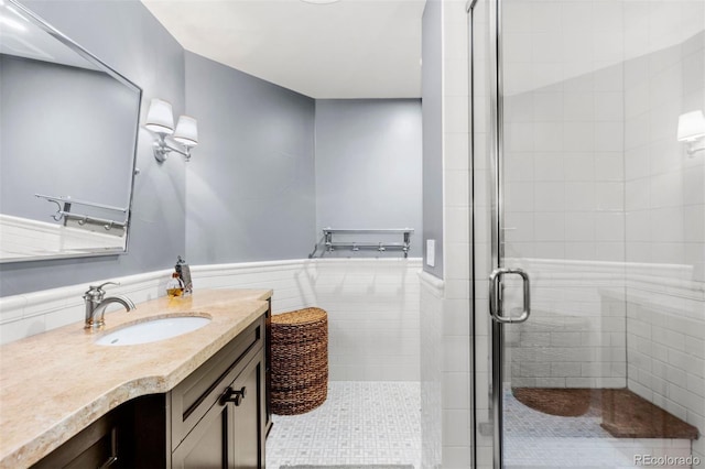 bathroom with a wainscoted wall, a stall shower, vanity, and tile walls