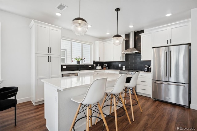 12270 W 57th Ave, Arvada, CO 80002 - kitchen featuring stainless steel appliances, wall chimney range hood, a sink, dark wood-type flooring, and decorative backsplash