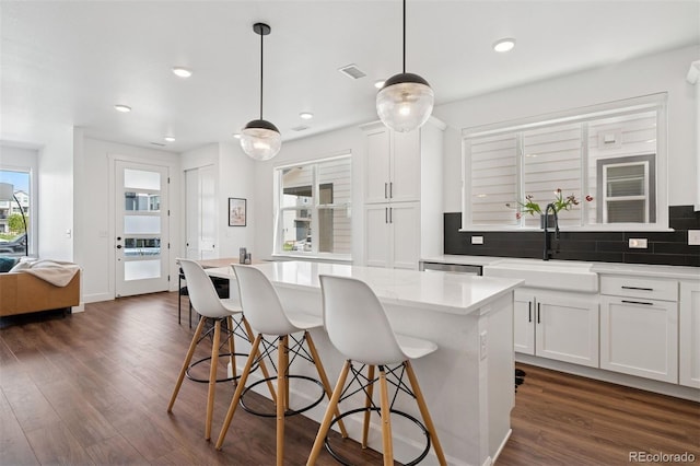 12270 W 57th Ave, Arvada, CO 80002 - kitchen with a breakfast bar, dark wood finished floors, decorative backsplash, a sink, and white cabinets