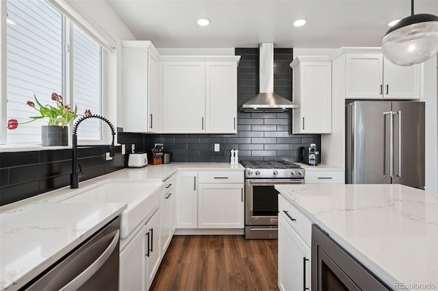 12270 W 57th Ave, Arvada, CO 80002 - kitchen featuring stainless steel appliances, wall chimney range hood, a sink, white cabinetry, and backsplash