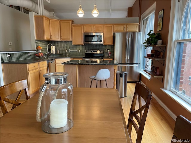 kitchen with pendant lighting, stainless steel appliances, a center island, and decorative backsplash