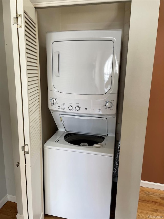 clothes washing area with stacked washer / drying machine and light hardwood / wood-style floors