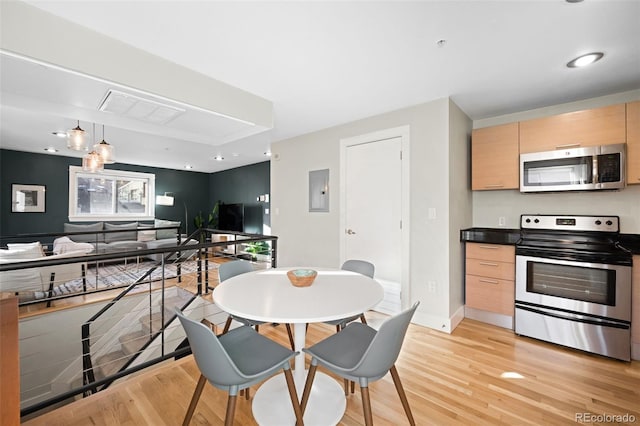 kitchen with electric panel, appliances with stainless steel finishes, light brown cabinetry, and light wood-type flooring