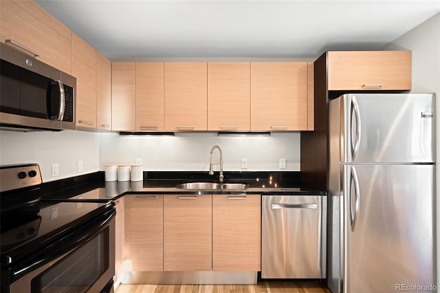 kitchen with dark countertops, modern cabinets, appliances with stainless steel finishes, and a sink