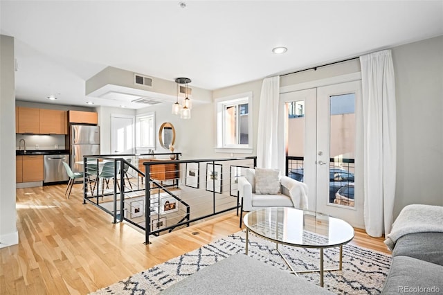 living room with light wood-style flooring, recessed lighting, french doors, and visible vents