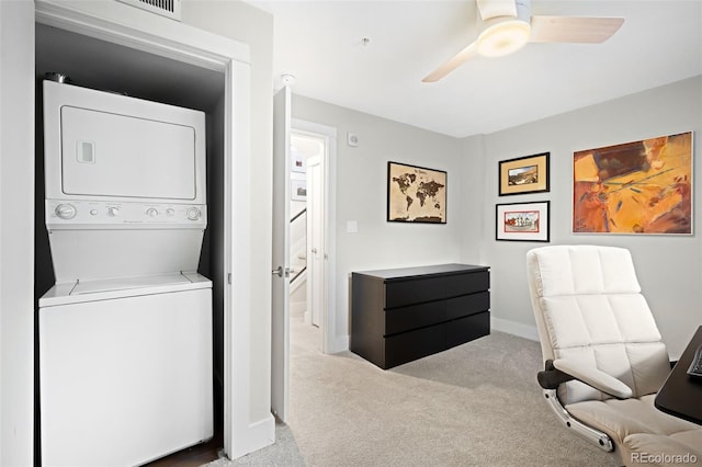 clothes washing area featuring baseboards, carpet floors, stacked washer and dryer, laundry area, and a ceiling fan