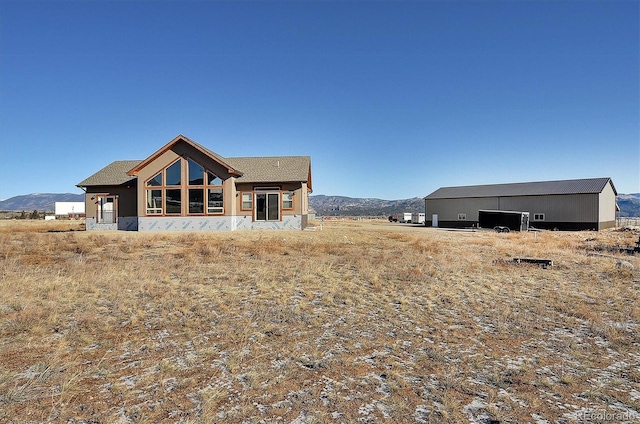 back of property featuring a mountain view and an outbuilding