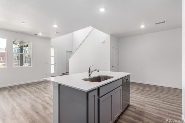 kitchen featuring a sink, gray cabinets, dishwasher, light wood finished floors, and light countertops