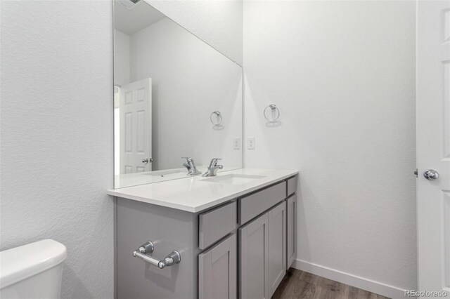 bathroom featuring wood finished floors, toilet, vanity, and baseboards