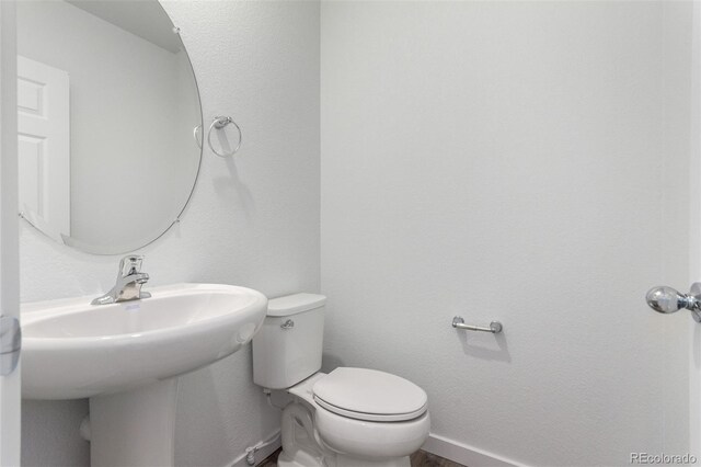 bathroom with toilet, baseboards, and a sink