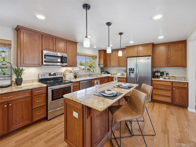 6490 S Pontiac Ct, Centennial, CO 80111 - kitchen with brown cabinets, hanging light fixtures, appliances with stainless steel finishes, a breakfast bar, and light wood-style flooring