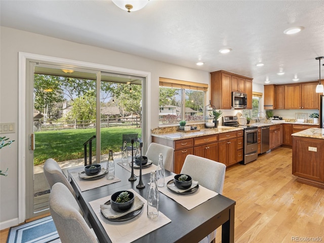 6490 S Pontiac Ct, Centennial, CO 80111 - kitchen with a healthy amount of sunlight, appliances with stainless steel finishes, brown cabinetry, and light wood finished floors