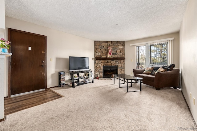 carpeted living room with a stone fireplace and a textured ceiling