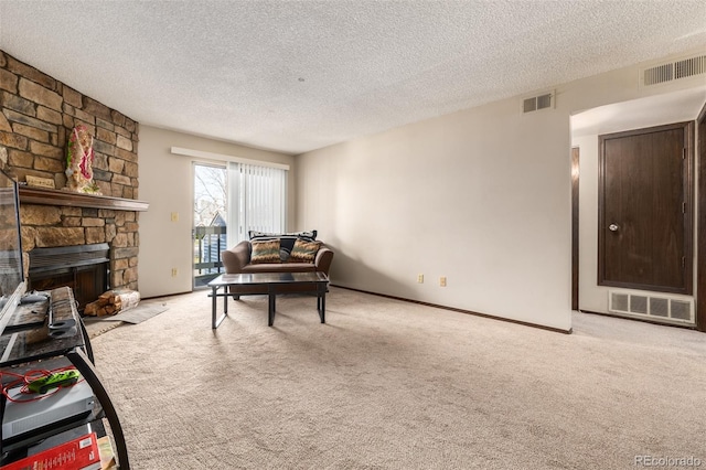 carpeted living room featuring a stone fireplace and a textured ceiling