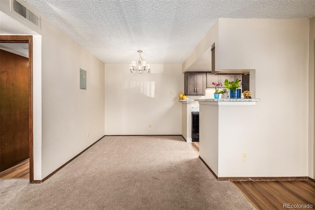 interior space featuring an inviting chandelier, a textured ceiling, and light carpet