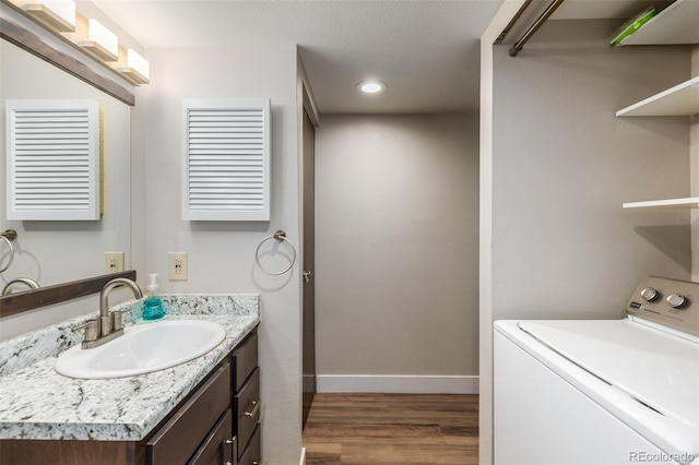 bathroom with hardwood / wood-style floors, washer / dryer, and vanity