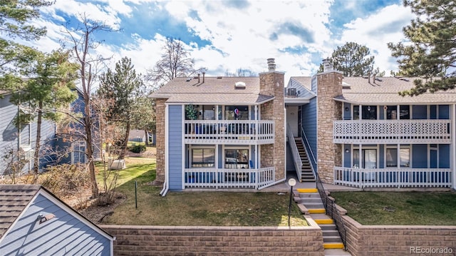 rear view of property with a balcony and a yard