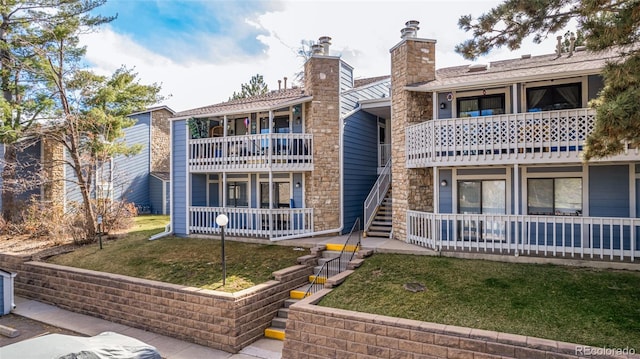 rear view of house featuring a balcony and a yard