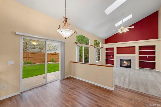 3371 Bexley Dr, Colorado Springs, CO 80922 - unfurnished living room with high vaulted ceiling, a skylight, wood finished floors, a tile fireplace, and baseboards