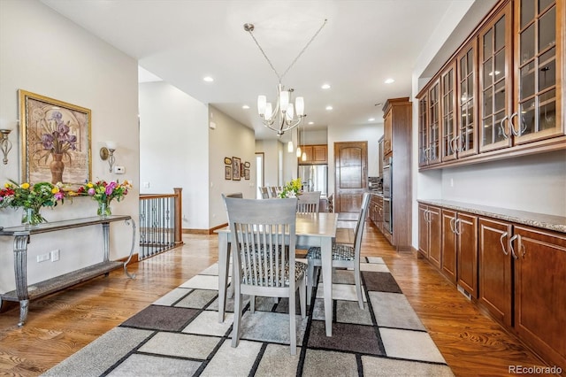 dining space with light wood-type flooring and a notable chandelier