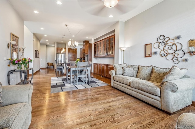 living room with light hardwood / wood-style flooring and ceiling fan with notable chandelier