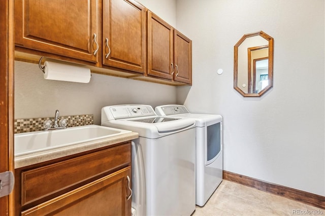 laundry room with sink, washing machine and clothes dryer, light tile patterned flooring, and cabinets