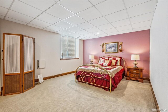 bedroom with a drop ceiling and light carpet